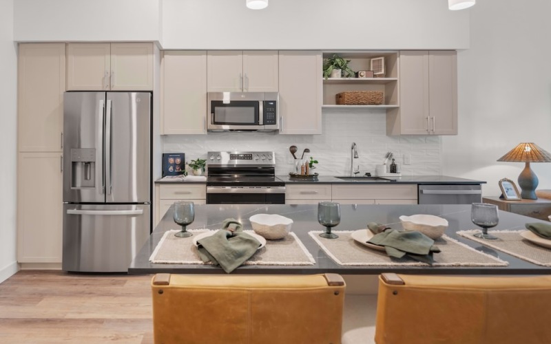 a kitchen with an island, two chairs, and stainless steel appliances in background